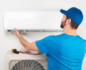 Installation service fix repair maintenance of an air conditioner indoor unit, by cryogenist technican worker in blue shirt baseball cap